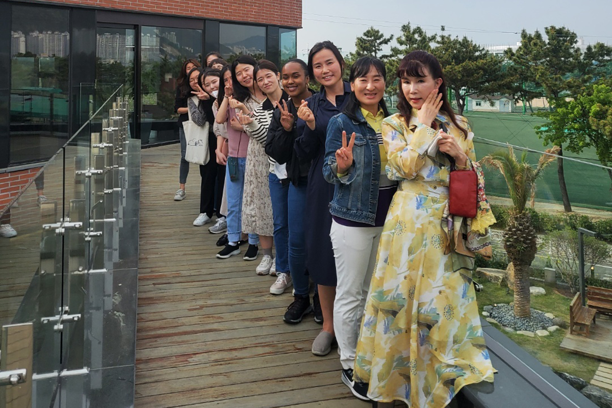 A group of female teachers stand together on a walkway