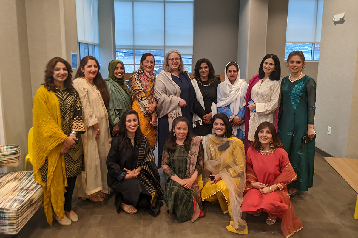 A group of women in Pakistani dress pose together for a photo.