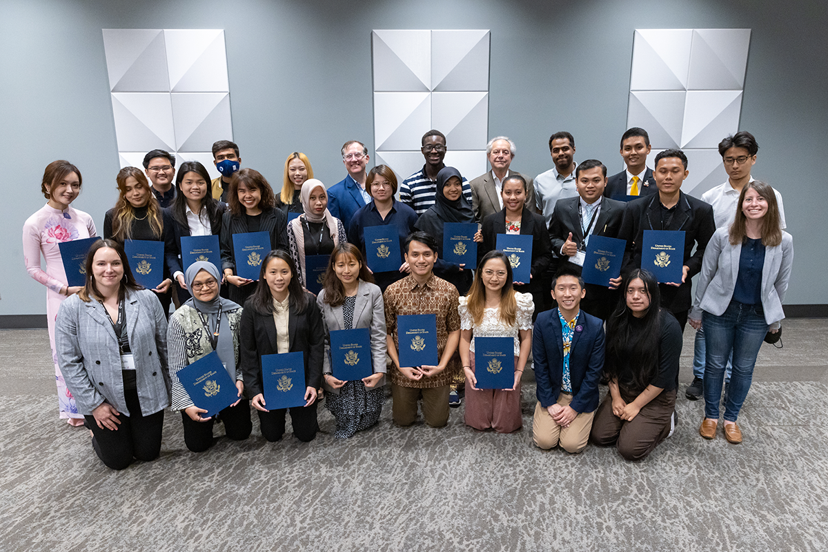 The May 2022 YSEALI cohort pose together at their farewell event, holding small replica passports.