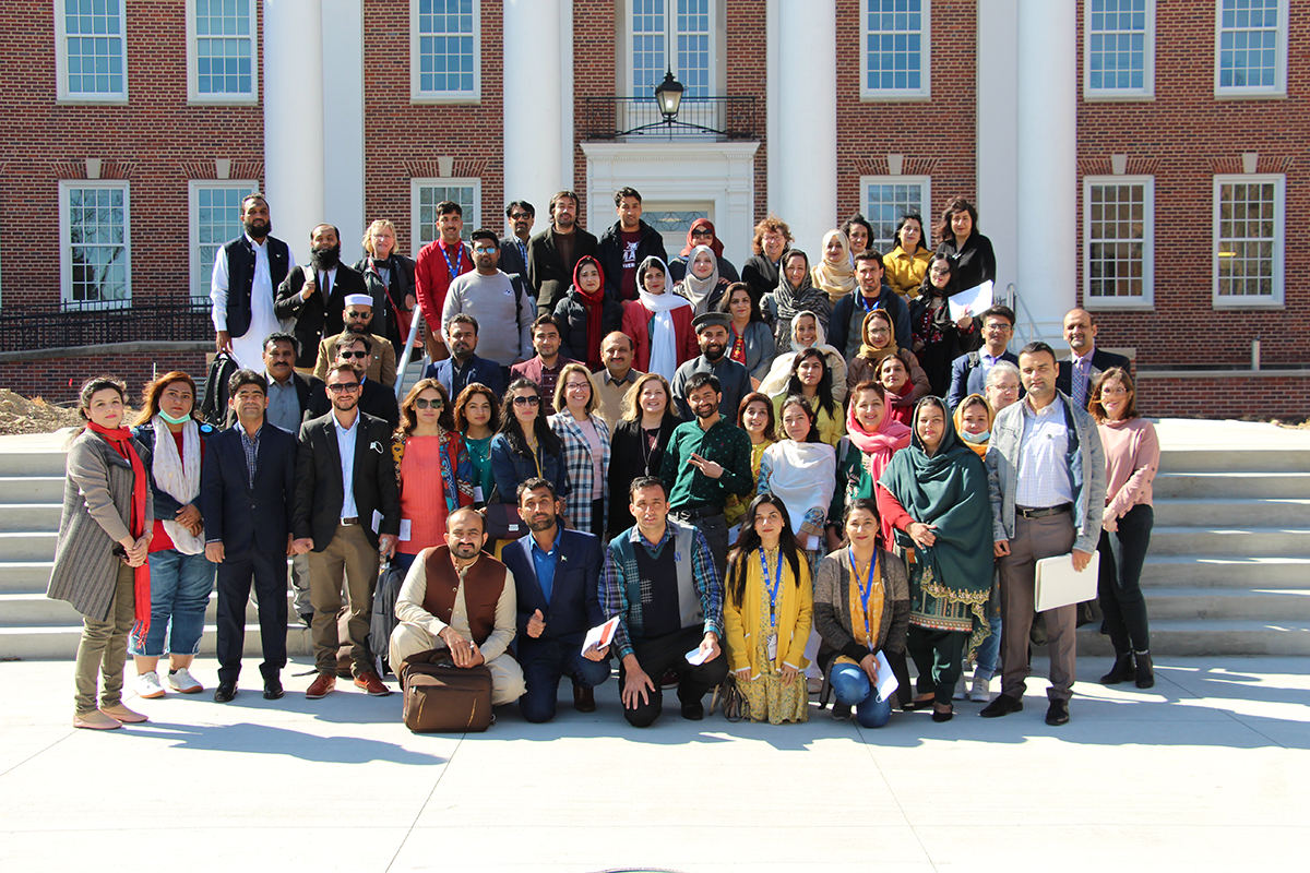 A large group of Pakistani English teachers and UNO staff stand on the steps of the Arts and Sciences Hall