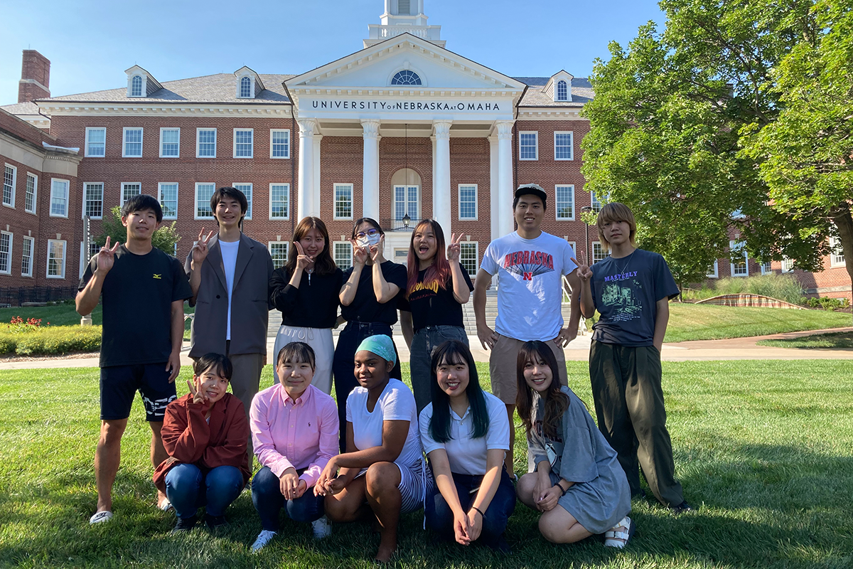 12 ILUNO students pose on the lawn in front of the Arts and Sciences Hall at UNO.