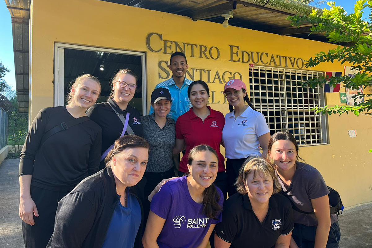 Students pose together in front of a yellow building in the Dominican Republic