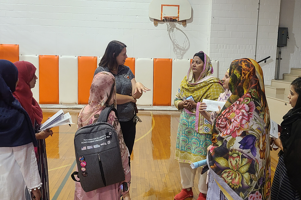 Pakistani English teachers stand in a school gymnasium with local staff