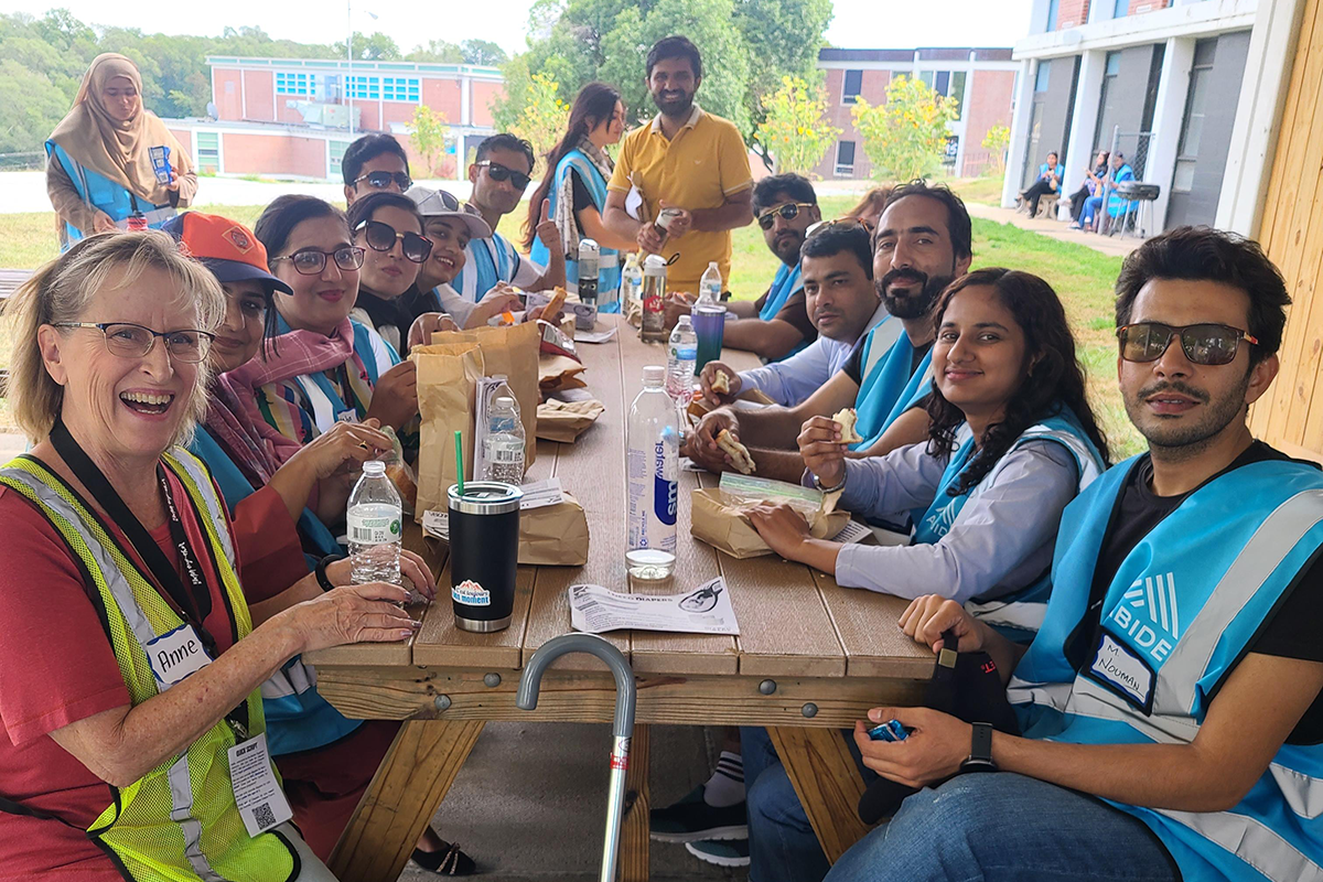 People eat lunch around a picnic table.