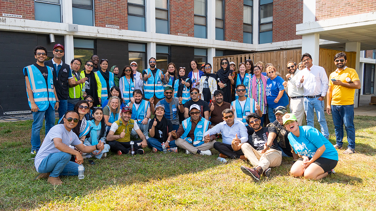 A group of volunteers pose together for a photo outside a brick building.