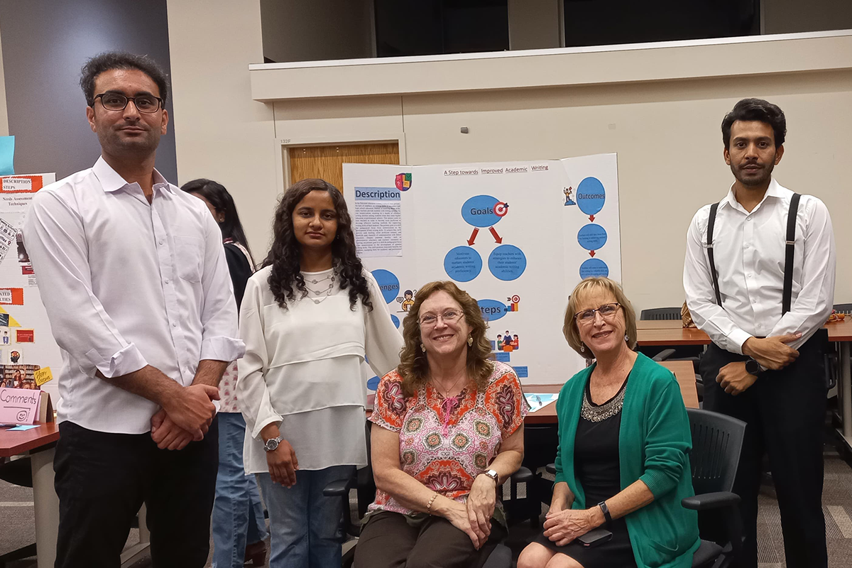 People pose around a project poster.