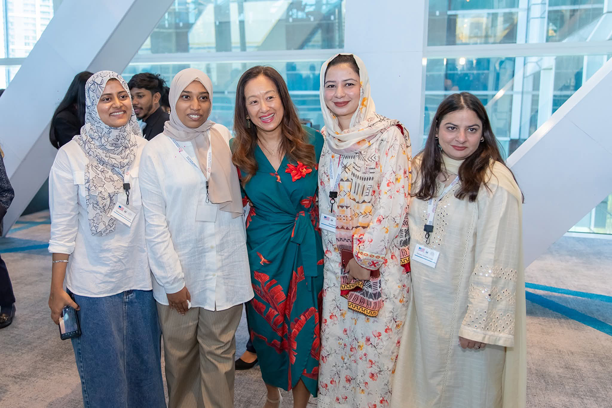 Five women pose together in a hotel conference area