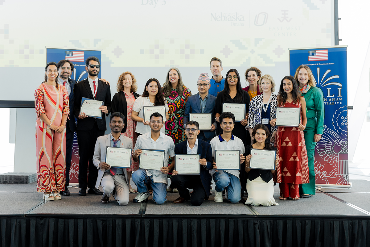 Group poses for a photo on a stage holding paper certificates.