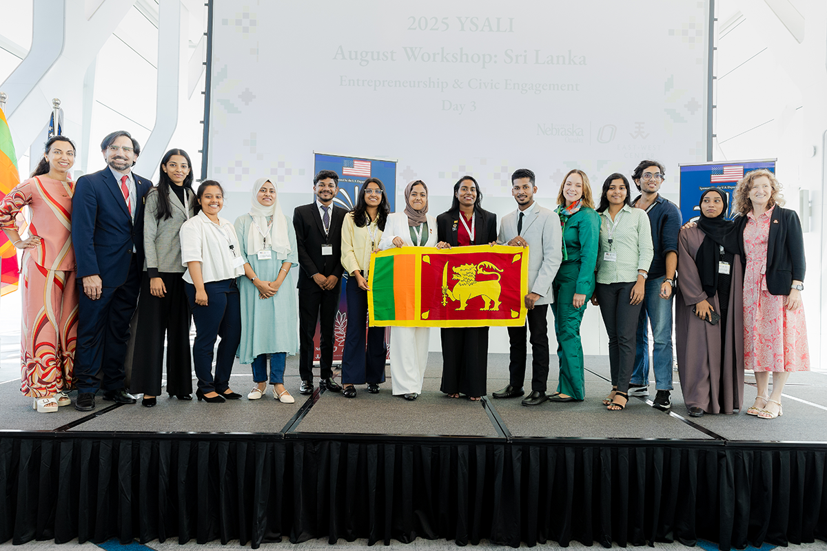 People stand on a stage holding a Sri Lankan Flag.