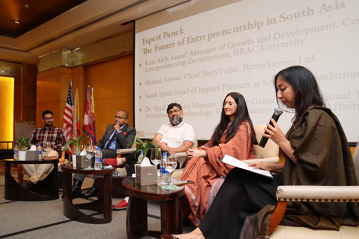 Women holds a microphone and speaks on a panel.