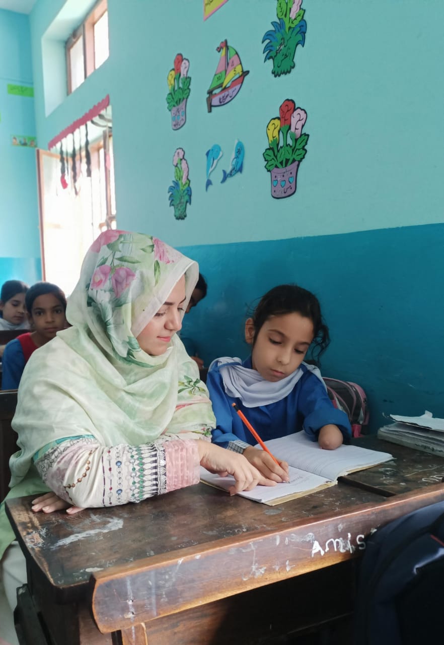Teacher and student sitting at a desk writing in a notebook.