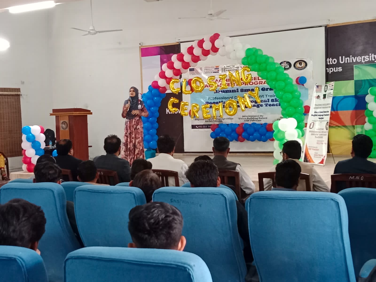 Woman on a stage speaks to a crowd at a closing ceremony.