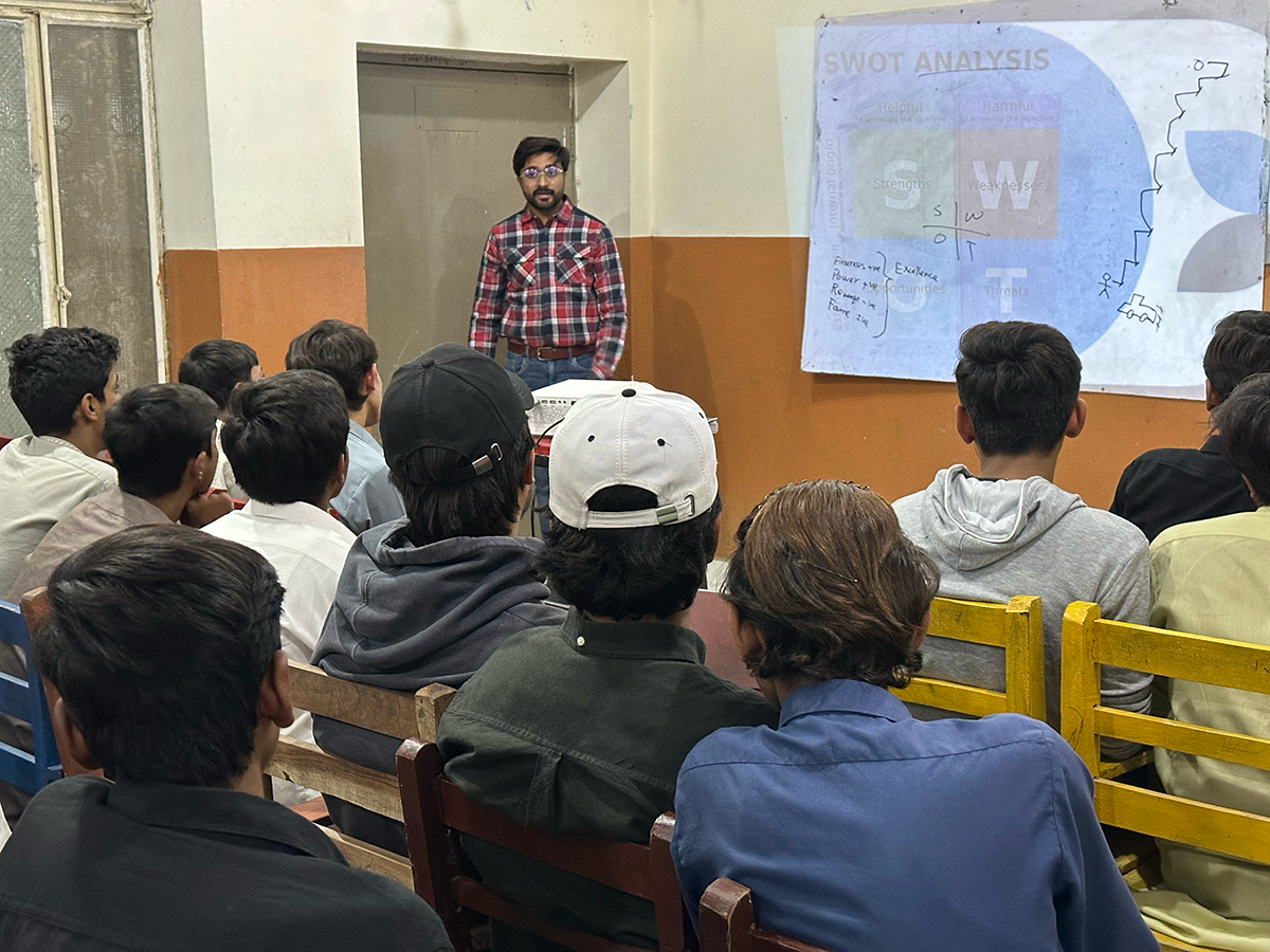A teacher stands at a whiteboard sharing a lesson.
