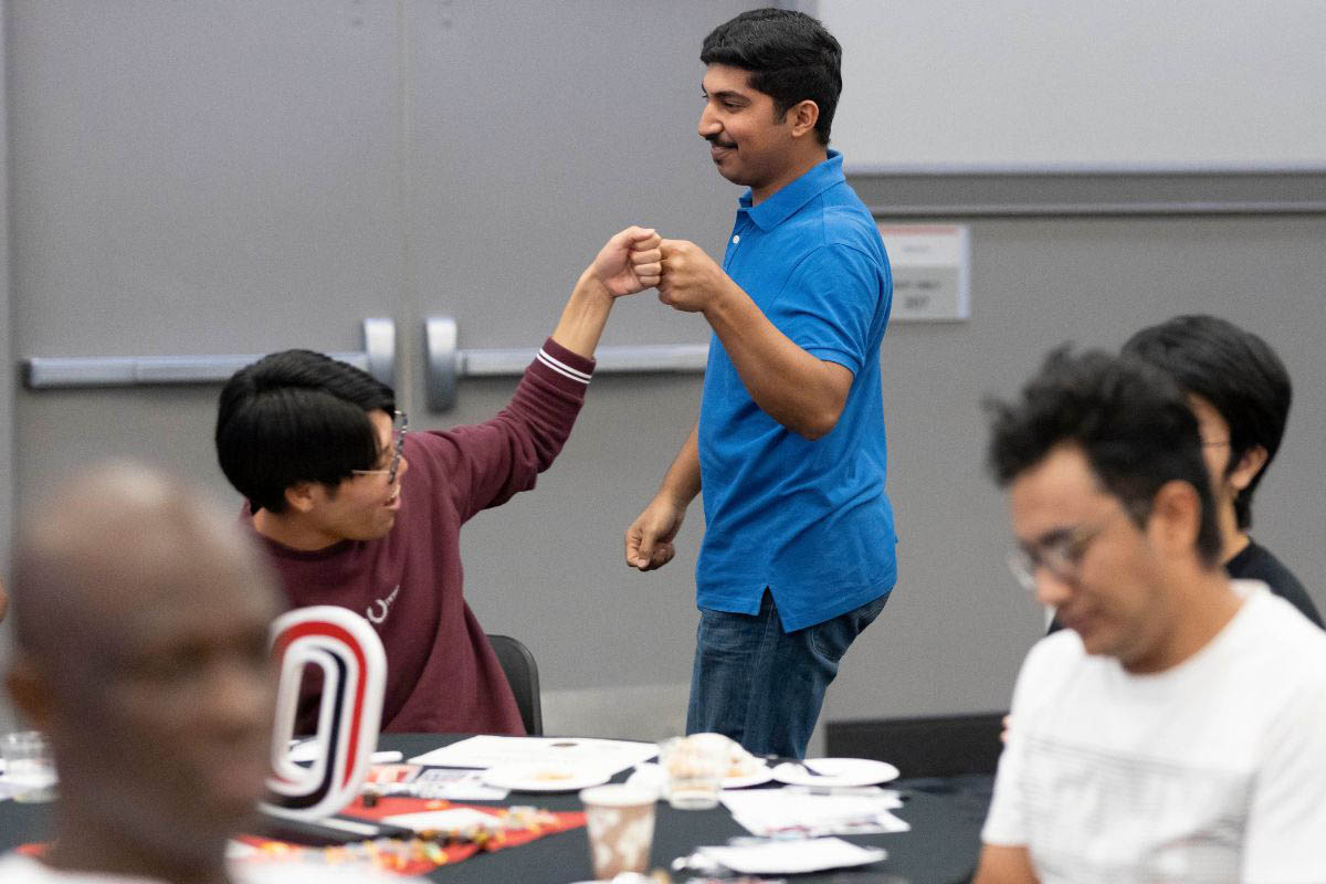 Two students greet one another with raised fists.