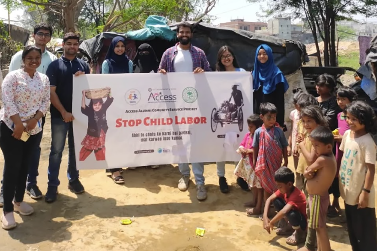 A group of children and adults stand together holding a sign that reads, 'Stop Child Labor'.