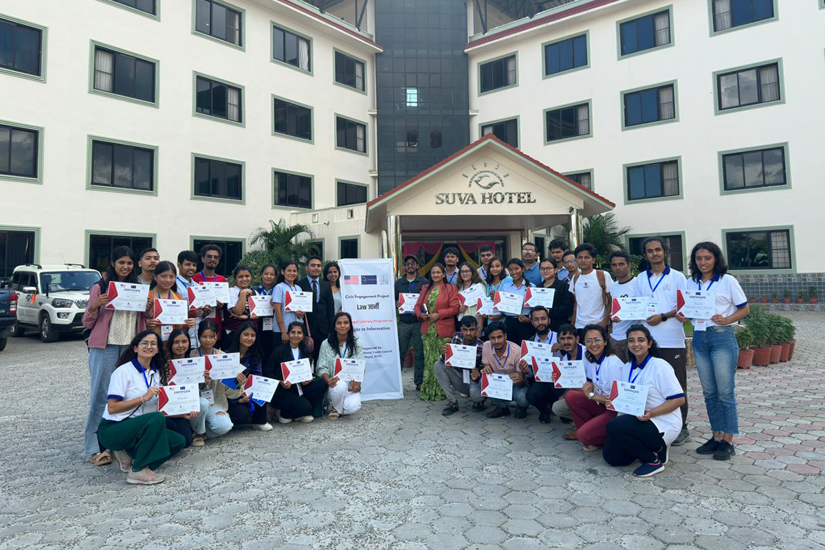 A group poses for a photo holding certificates outside the entrance to the Suva Hotel.