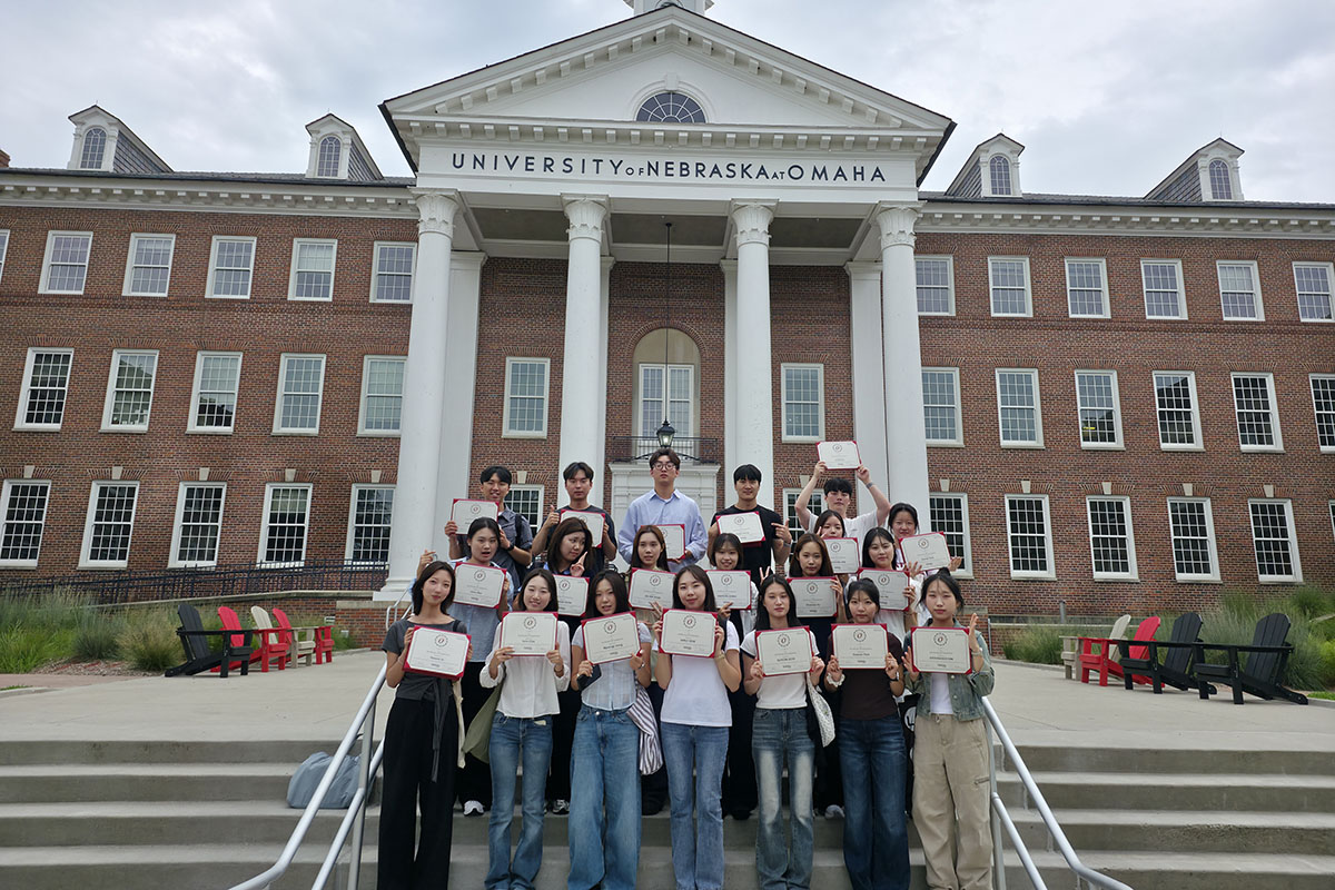 Students pose with certificates in front of UNO Arts and Science hall
