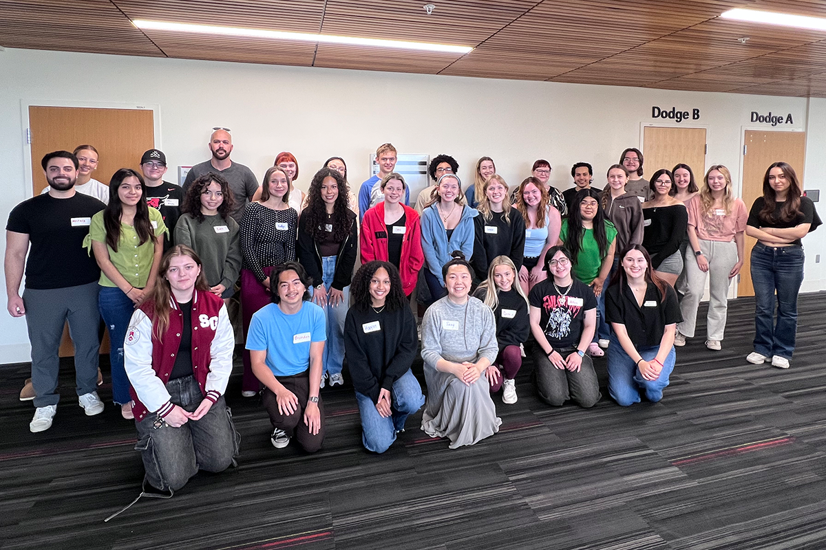 A mid-size group of college students poses together indoors.
