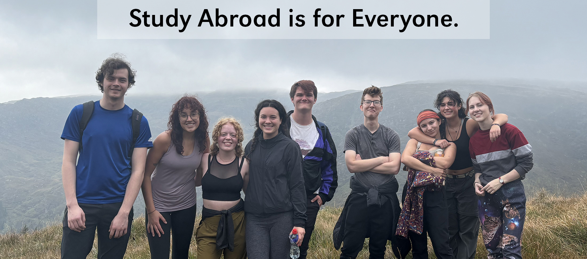 Group of college students stand on a grassy hilltop with a cloudy sky in the background. Study Abroad is for Everyone is written across the top of the image in black text.