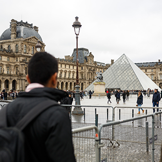 Man stands in the foreground looking at the Louvre