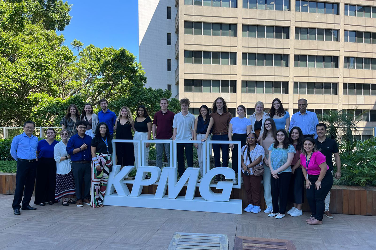 Group posing around a KMPG business sign