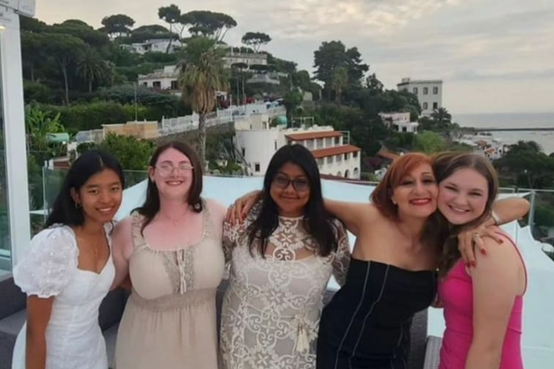 Friends pose together with an Italian hillside in the background.