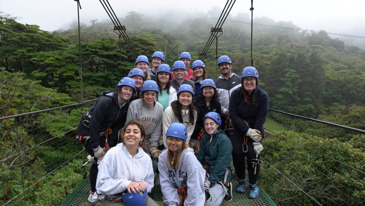 Group of people wearing helmets on a suspension bridge.