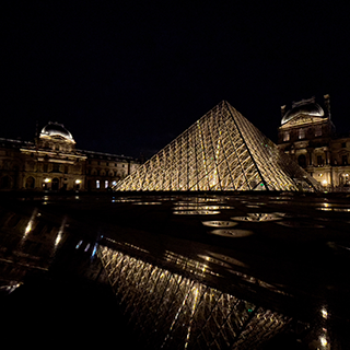 The Louvre Museums's glass pyramid lit up at night.