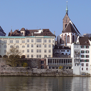 A church and other buildings line a riverfront.