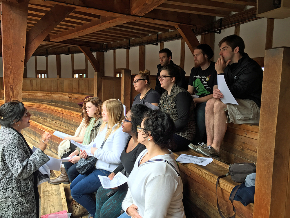 Students sit in the Globe Theatre listening to a speaker.
