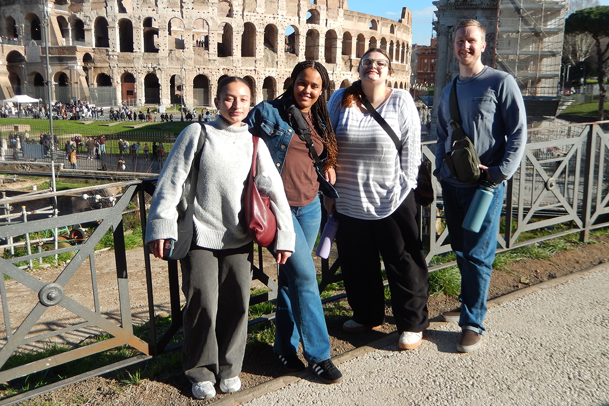 four college students pose in front of the Colosseum in Rome.