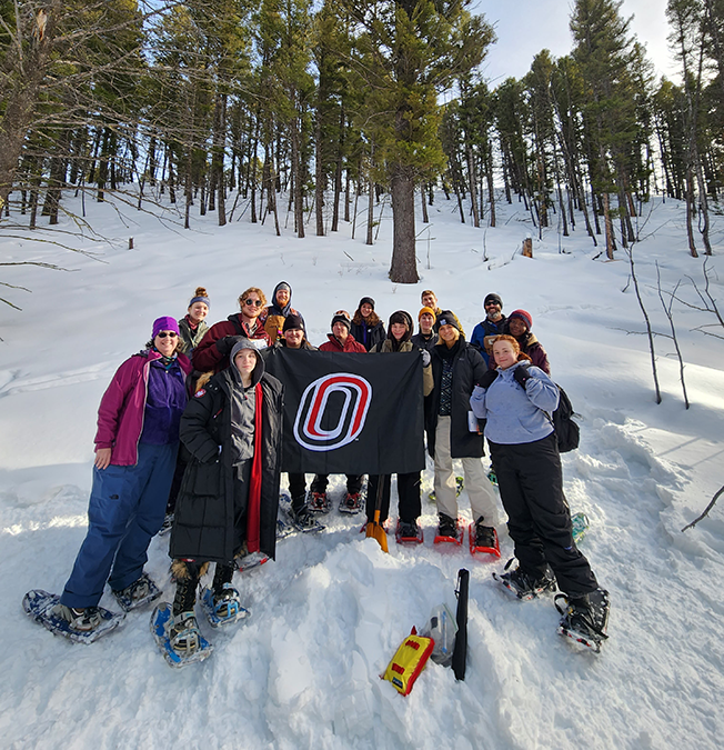 Winter Ecology in Yellowstone group poses with the UNO flag during a snowshoe hike.