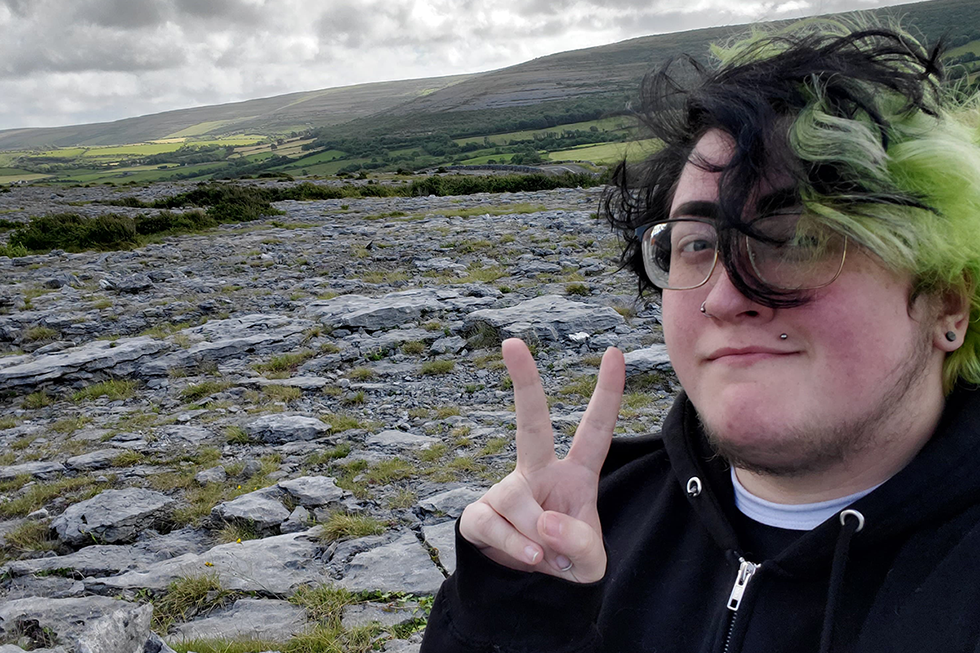 UNO student Kirk flashes a peace sign with his hand in front of the rocky Burren.