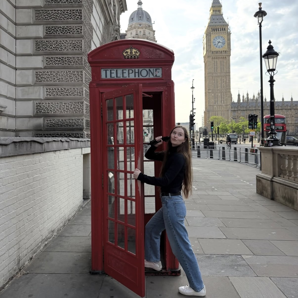 Student pretending to take a call in a red phone booth