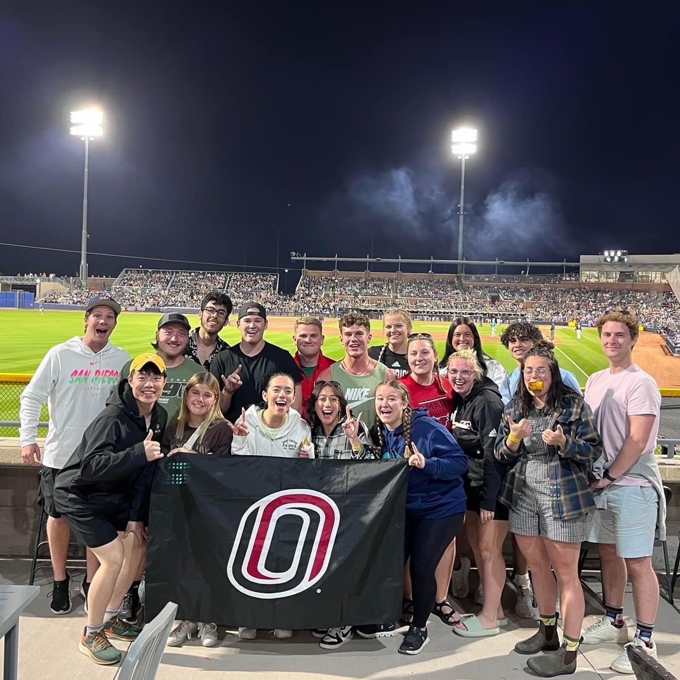 Student group at baseball field with UNO flag