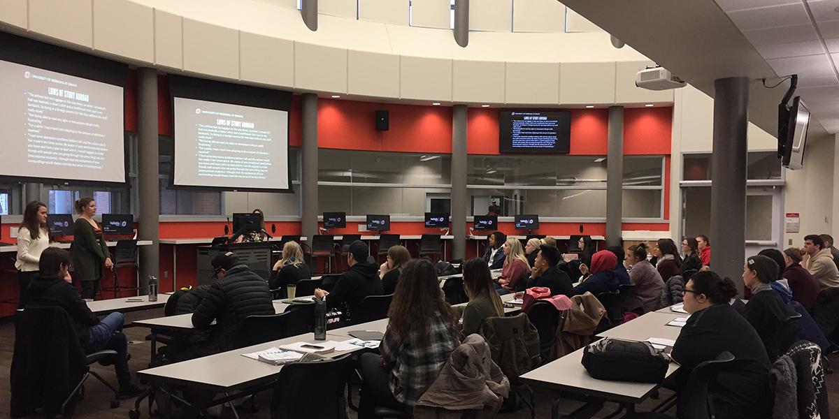 students sitting in a classroom listening to two student speakers share about study abroad