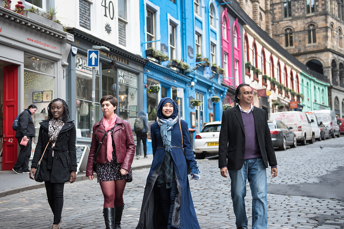 4 students walk down the street in Edinburgh, Scotland.