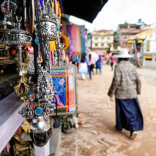 Woman wearing a hat walks past a stall in a market in Nepal.