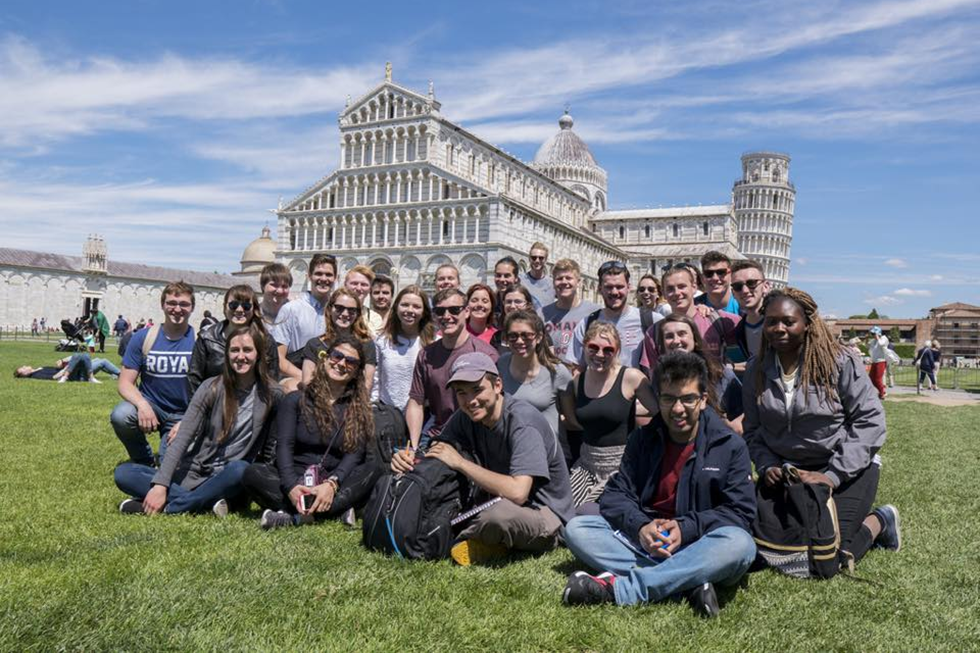 Students sit in front of a classical building in Italy