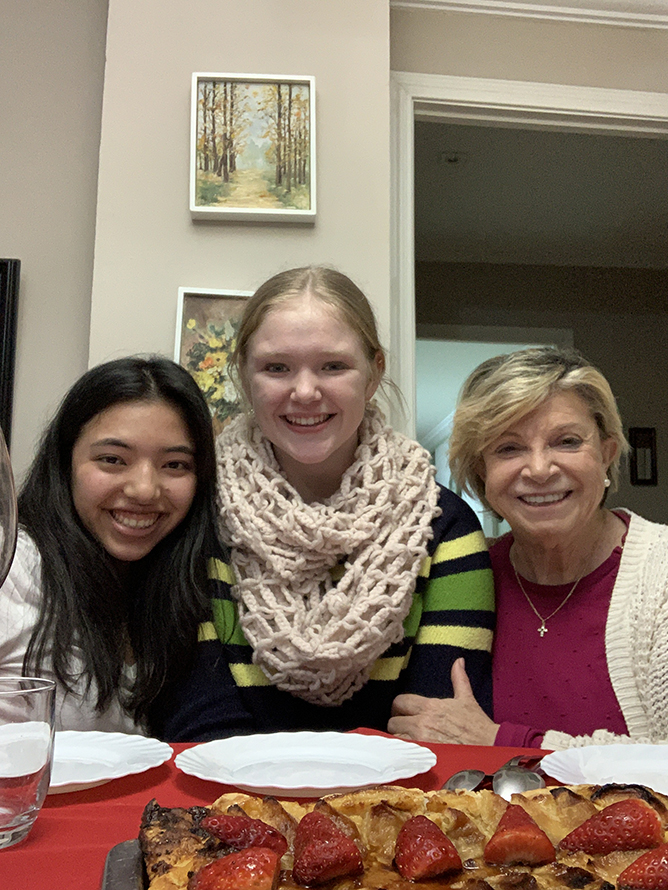 two girls and one woman stand together smiling, they are a host family in Spain