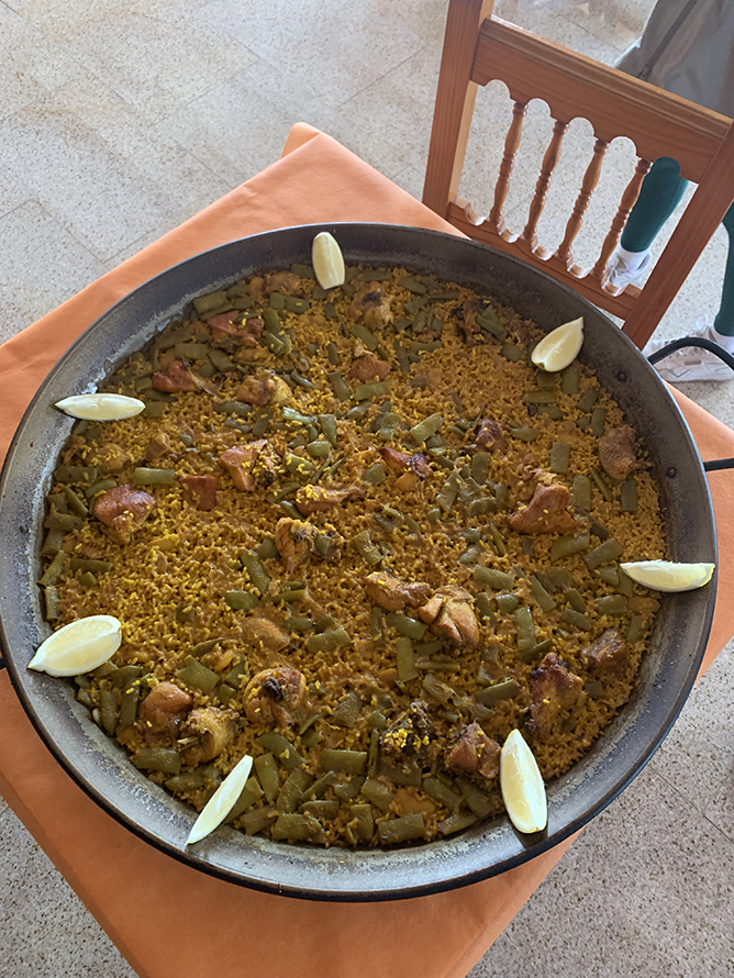A wide shallow pan of paella sits on a table