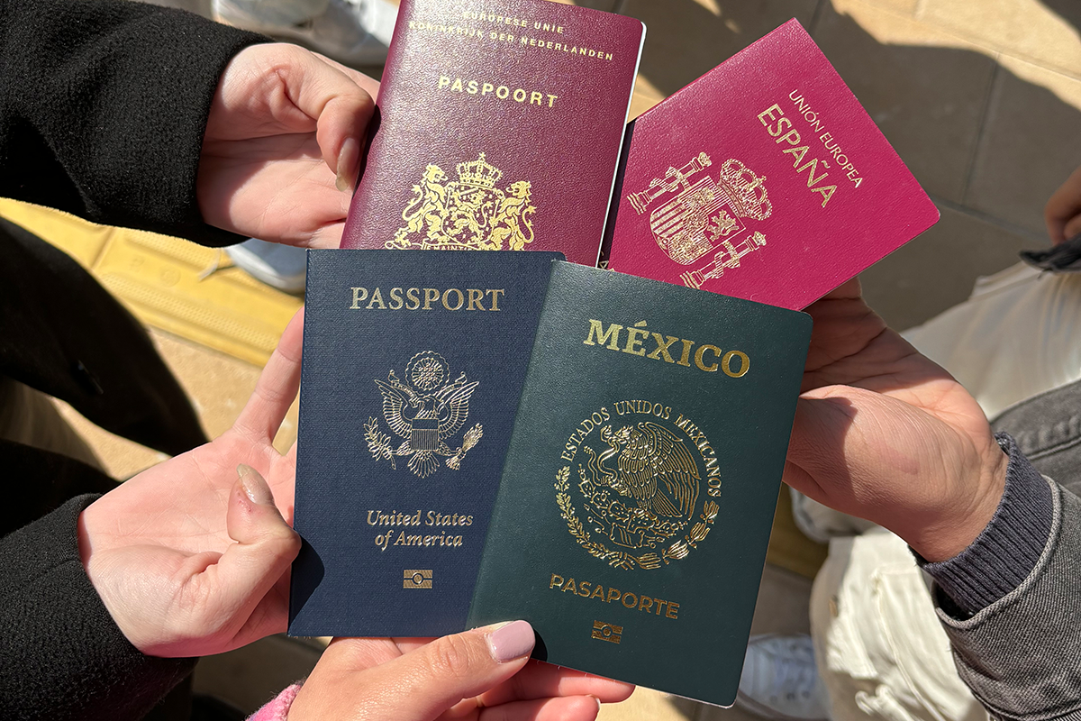 Hands hold four passports together in the middle, from the Netherlands, Spain, Mexico, and the United States.