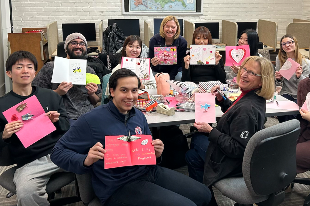Group of college students pose with homemade Valentine's Day cards.
