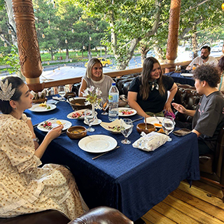 Four people sit around a table with food, talking with each other.