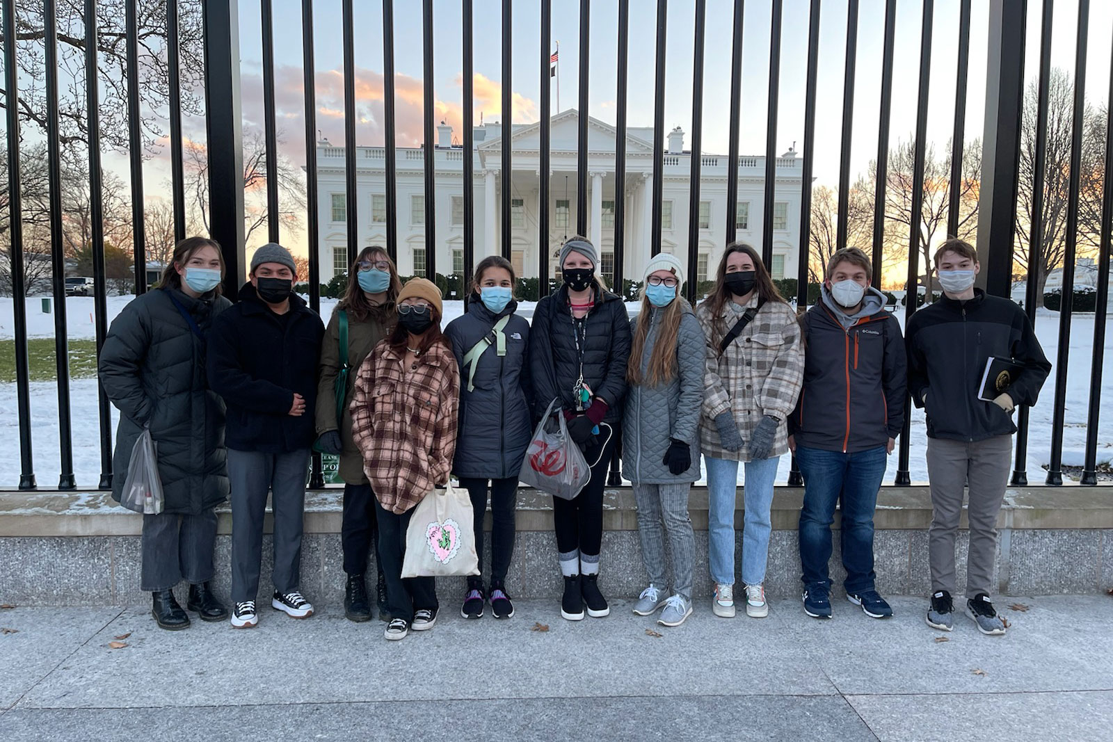 UNO students pose against a black fence in front of the White House in Washington DC