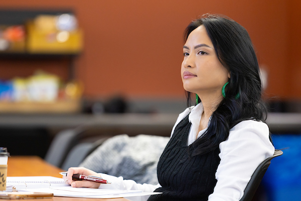 a young hispanic woman holds a pen and is ready to take notes during a lecture.