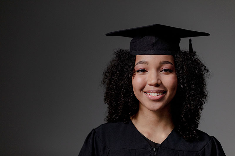 A graduate smiles as they wear their gown and mortar board. 