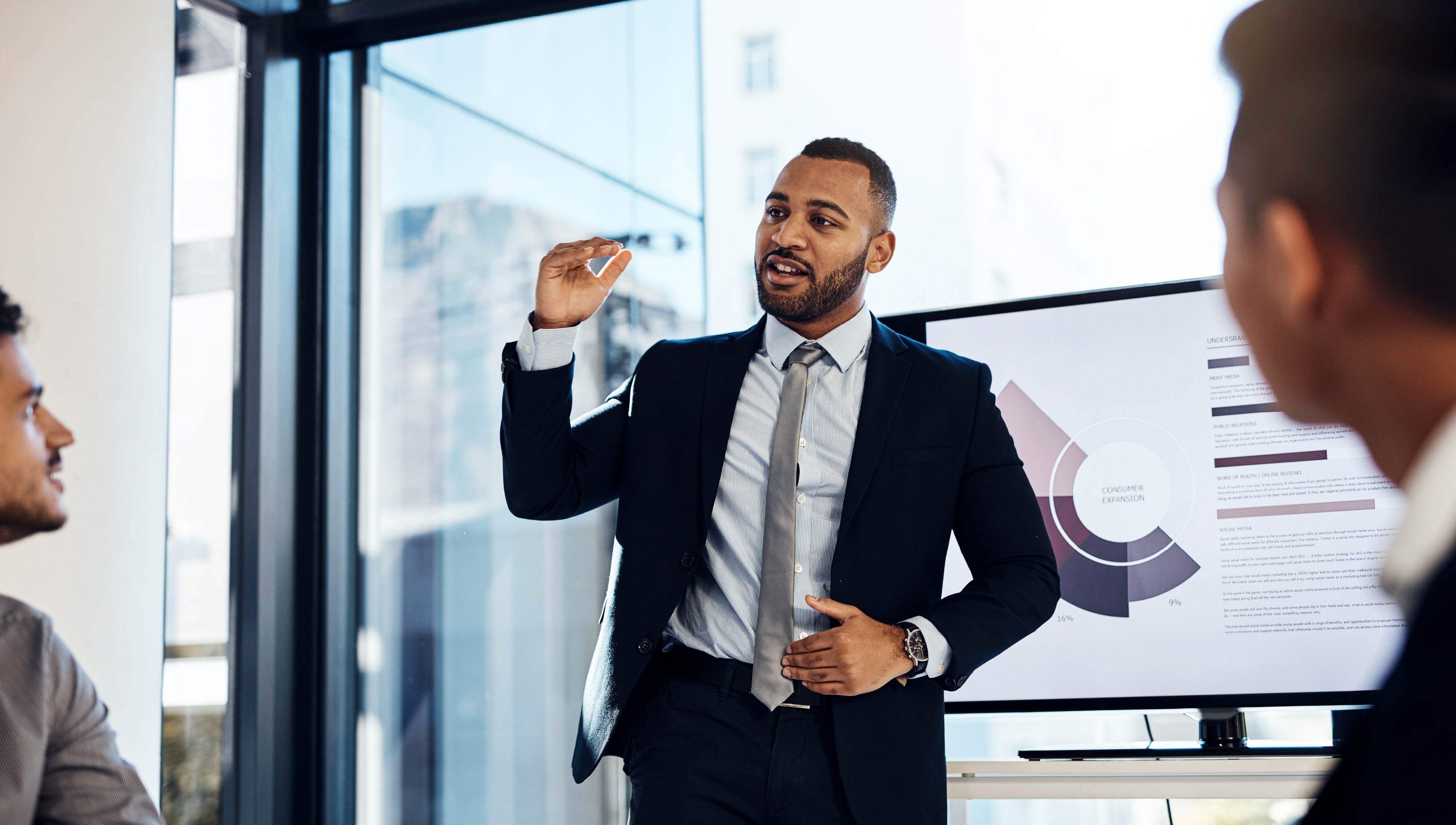Business professional presenting data to colleagues during a meeting in a modern office.