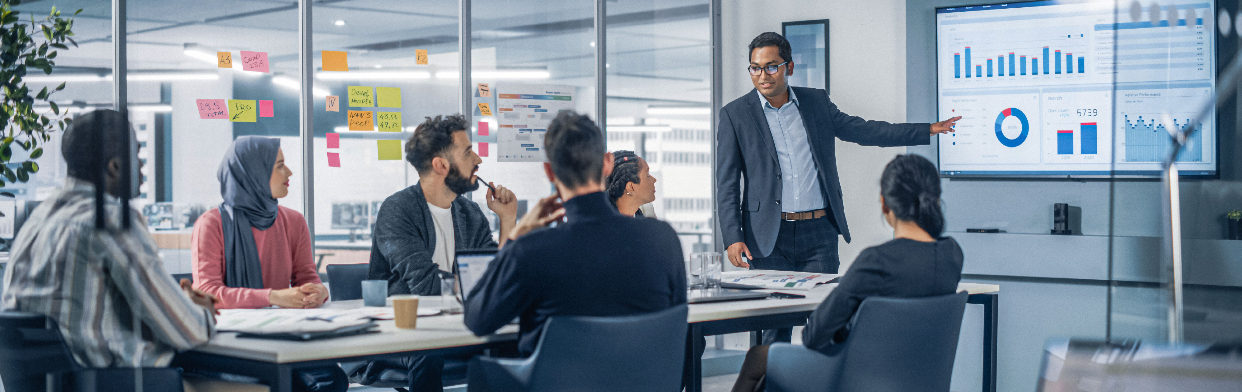 Business professionals in a meeting, with one person presenting data on a screen to a team