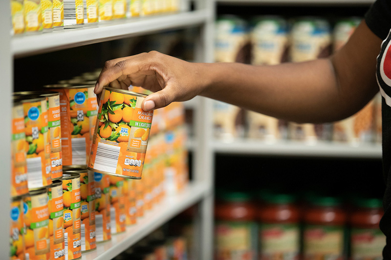 hand placing a can of food on a shelf